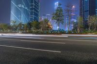 a city street with buildings and neon lights at night time in hong china as seen from an empty city highway