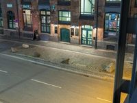 an empty street with an arrow on the road sign at night and people outside on the street