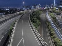 an empty highway in front of buildings in a large city at night with the lights on