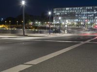 large building on the street with lights in front and other buildings nearby at night with no one moving