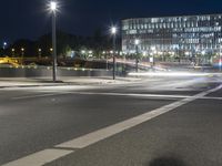 large building on the street with lights in front and other buildings nearby at night with no one moving