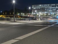 large building on the street with lights in front and other buildings nearby at night with no one moving