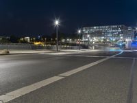 large building on the street with lights in front and other buildings nearby at night with no one moving