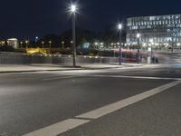 large building on the street with lights in front and other buildings nearby at night with no one moving