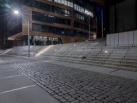 a city street lined with stairs, near a building at night, in the daylight