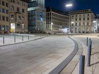 a night scene in a city with people walking around the plaza and sitting on benches