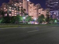 a street lined with tall buildings on both sides of the road at night as the sun shines through their windows