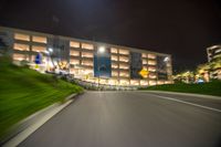 a speeding car near a building with several parking signs lit up at night time as seen from behind it