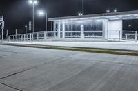 empty public shelter at night with lights on it and concrete flooring on the ground