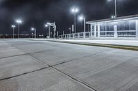 empty public shelter at night with lights on it and concrete flooring on the ground