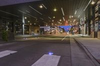 a city street at night with lights on both sides of it and empty sidewalks to the side