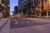 a city street at night with lights on both sides of it and empty sidewalks to the side
