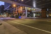 a city street at night with lights on both sides of it and empty sidewalks to the side