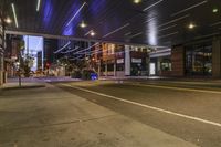 a city street at night with lights on both sides of it and empty sidewalks to the side