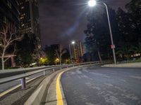 an empty city street is lit by street lights and buildings during night time in the city