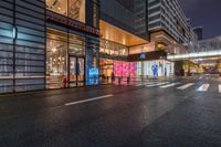 a city street with a storefront near by and buildings at night lights from windows