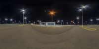 an empty parking lot at night with street lights on all sides of it and no people in the distance