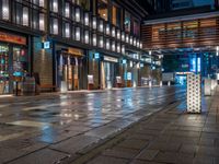 a large brick sidewalk with a store front at night time and a sign that says