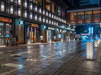 a large brick sidewalk with a store front at night time and a sign that says