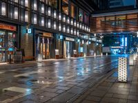 a large brick sidewalk with a store front at night time and a sign that says