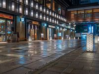 a large brick sidewalk with a store front at night time and a sign that says