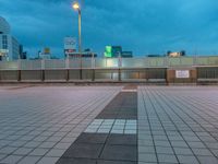 people standing on a subway platform with many buildings in the background at night light in tokyo