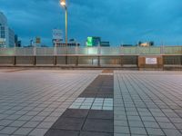 people standing on a subway platform with many buildings in the background at night light in tokyo