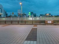 people standing on a subway platform with many buildings in the background at night light in tokyo