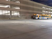 a large yellow bus is parked in the parking lot with other buses behind it and some lights