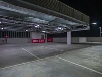 an empty parking garage with no one on the floor at night with lights coming from behind