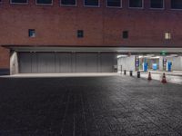 an empty parking garage at night next to a building with two open doors and no cars in front