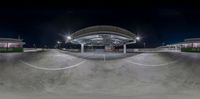 an empty parking garage at night with a skateboarder doing tricks on the ramp