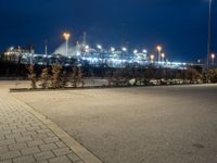 a parking lot next to a stadium at night with lights on the side of the building