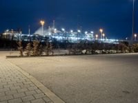 a parking lot next to a stadium at night with lights on the side of the building