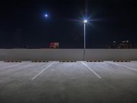 empty parking lot with street lights in the dark at night under a bright full moon