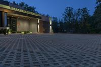 a photo taken at night of the front of a building at dusk with lights on and landscaping lighting up