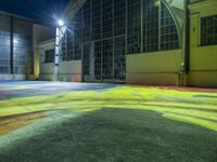 colorfully painted playground in front of large building at night, lit with streetlights