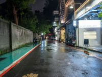 the wet road is lined with parked motorcycles and scooters in the rain at night