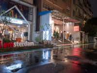 a storefront at night in the rain with its doors open and shoppers at their counter