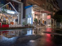 a storefront at night in the rain with its doors open and shoppers at their counter