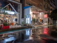 a storefront at night in the rain with its doors open and shoppers at their counter