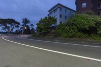 a man is riding down the side of a road next to trees on the side