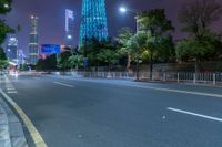 a city street with buildings and neon lights at night time in hong china as seen from an empty city highway