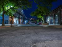 a city street at night with parking meters on either side and the road in the center