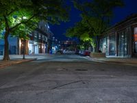 a city street at night with parking meters on either side and the road in the center