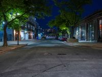 a city street at night with parking meters on either side and the road in the center