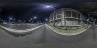 a fish - eye view of a road on a night with street lamps and buildings