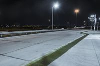 a road with lights on at night as a stop light watches from behind it and a freeway