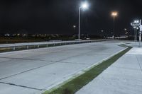 a road with lights on at night as a stop light watches from behind it and a freeway