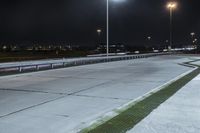 a road with lights on at night as a stop light watches from behind it and a freeway